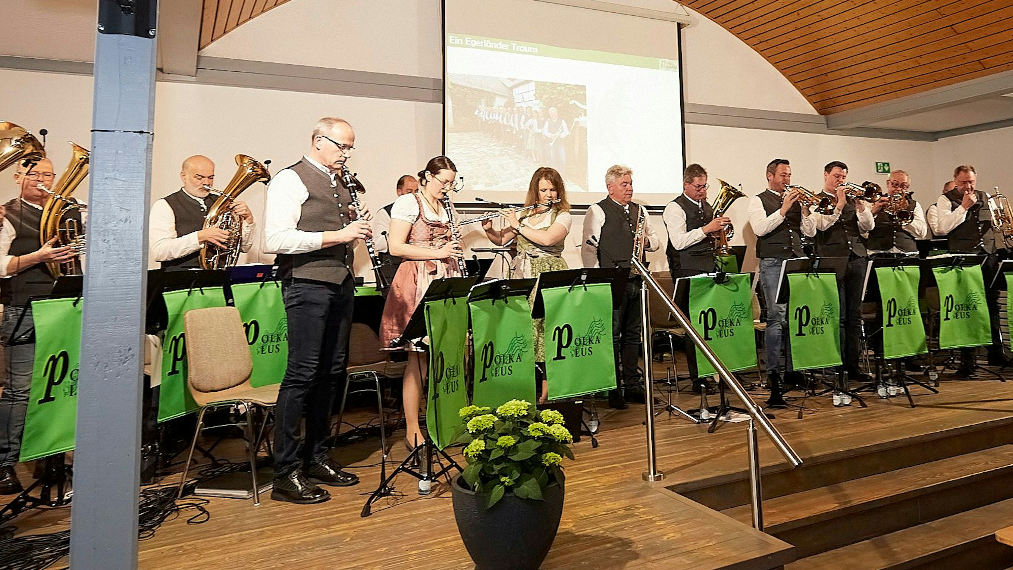 Das „Polka Plus“-Ensemble steht auf der Bühne und spielt auf Blasinstrumenten.