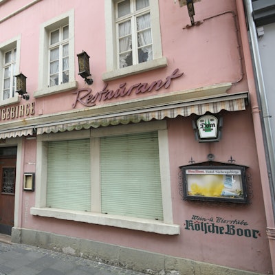 Ein ehemaliges Restaurant mit geschlossenen Rollläden an zwei Fenstern in der Fußgängerzone von Königswinter
