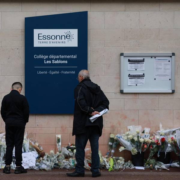 Anwohner betrachten die Blumen, die vor dem Eingang der Mittelschule Les Sablons in Viry-Chatillon niedergelegt worden sind.