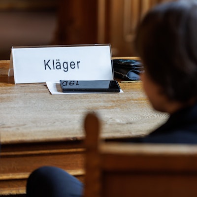 ARCHIV - 03.07.2023, Bayern, Bamberg: Eine Frau, die den Impfstoffhersteller Astrazeneca auf Schadenersatz verklagt, sitzt vor Beginn einer Berufungsverhandlung im Oberlandesgericht (OLG) Bamberg.