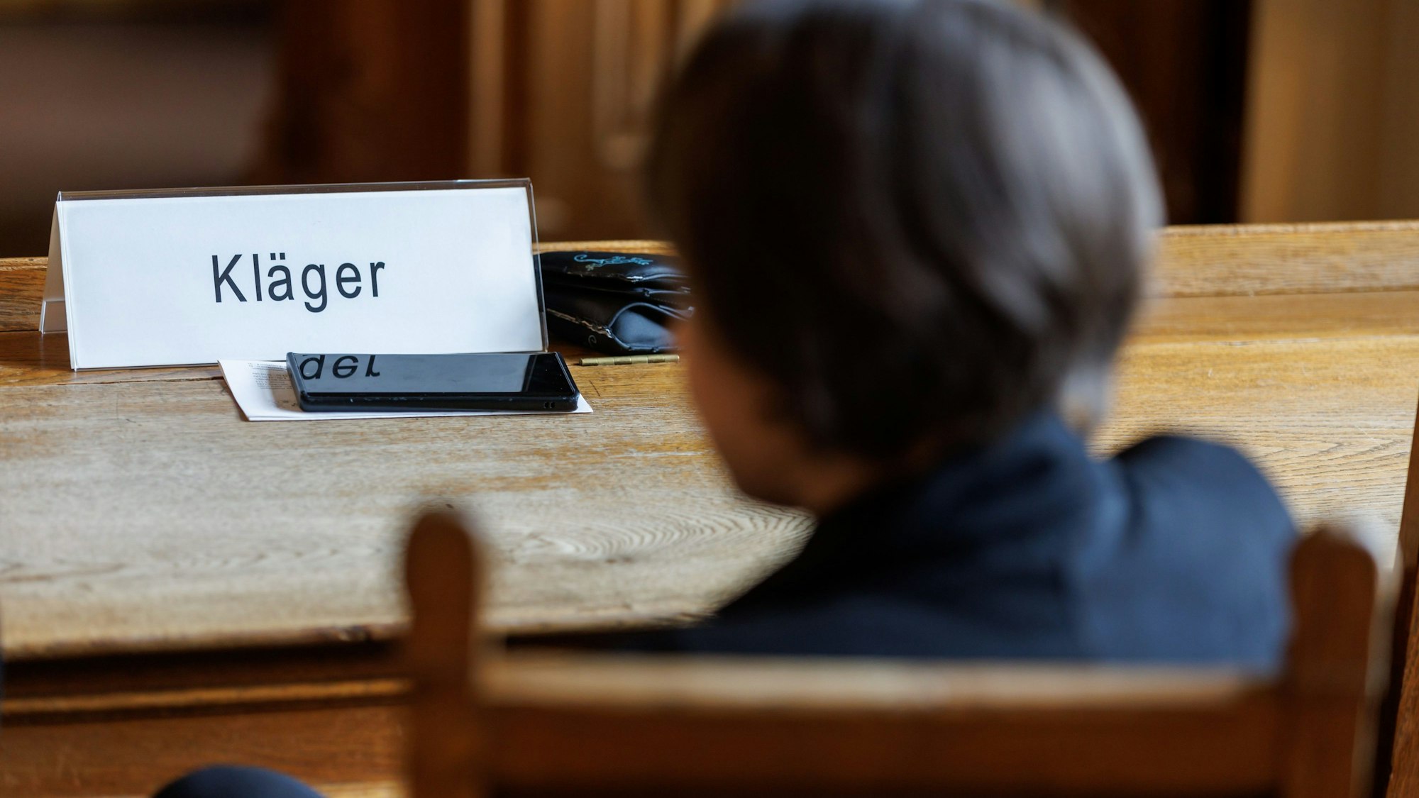 ARCHIV - 03.07.2023, Bayern, Bamberg: Eine Frau, die den Impfstoffhersteller Astrazeneca auf Schadenersatz verklagt, sitzt vor Beginn einer Berufungsverhandlung im Oberlandesgericht (OLG) Bamberg.