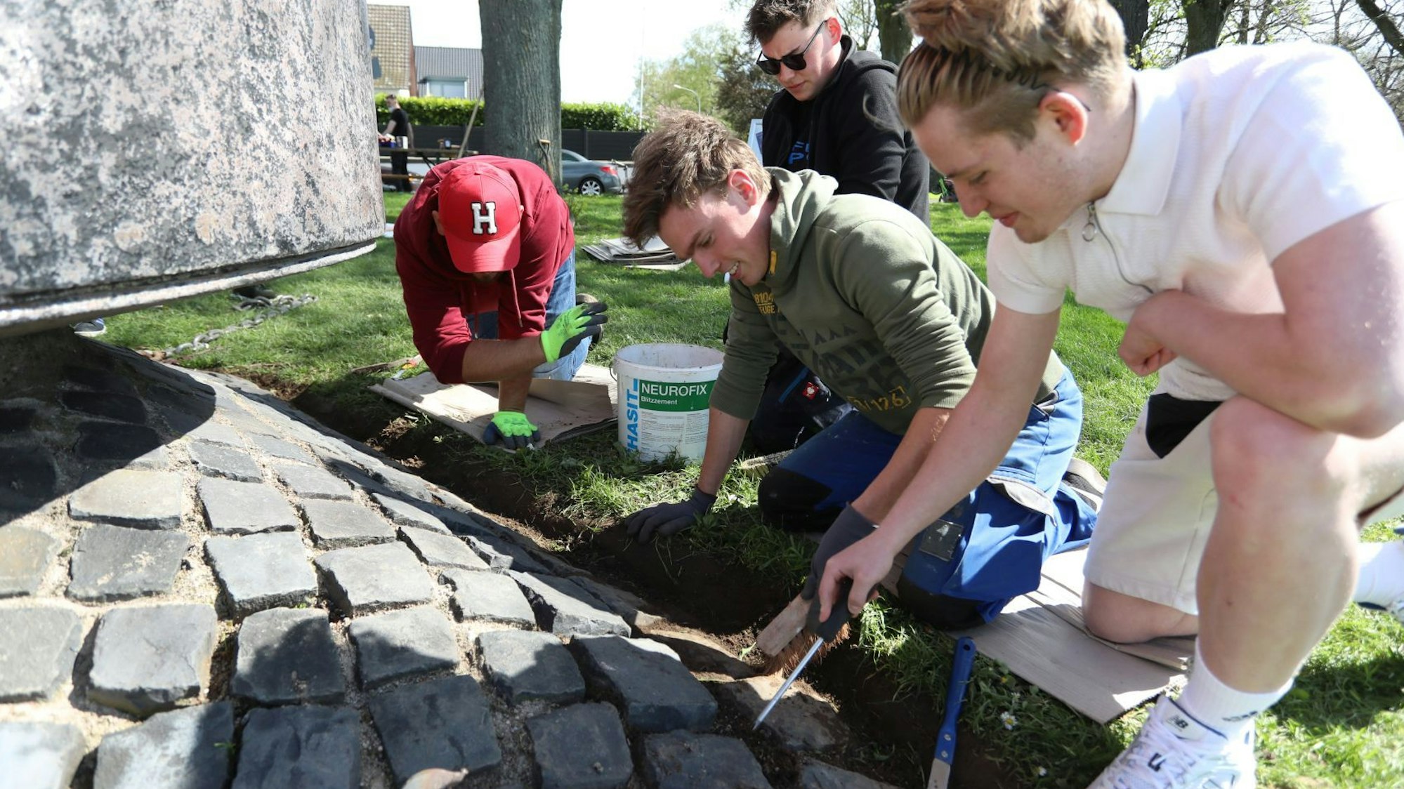 Mehrere junge Männer beseitigen Unkraut am Fundadement der Boje.