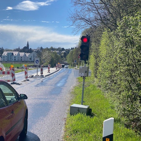 Zu sehen ist ein Auto, das vor der Bedarfsampel steht und dessen Fahrer auf Grünlicht wartet.