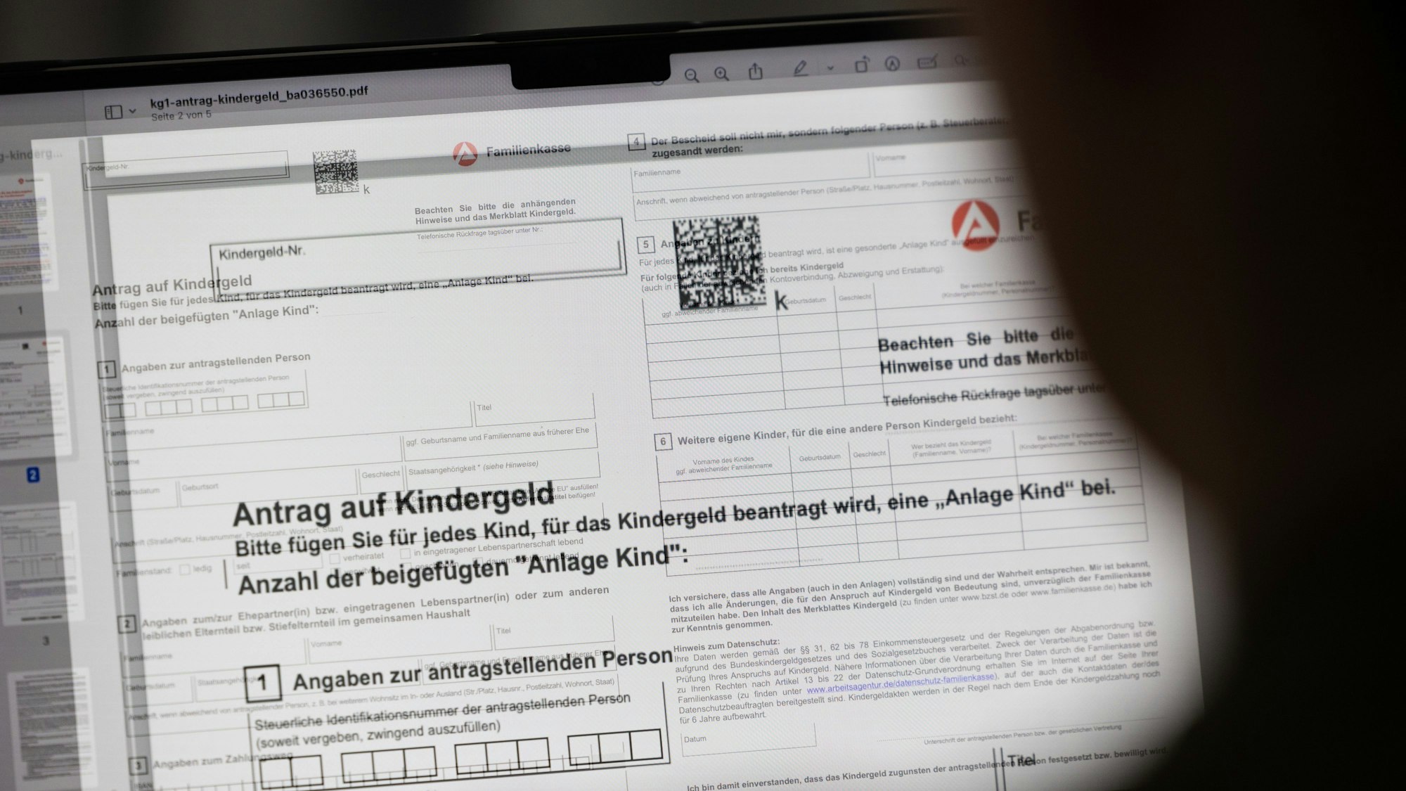 Ein Mensch sitzt vor einem Kindergeld-Antrag an einem Computer.