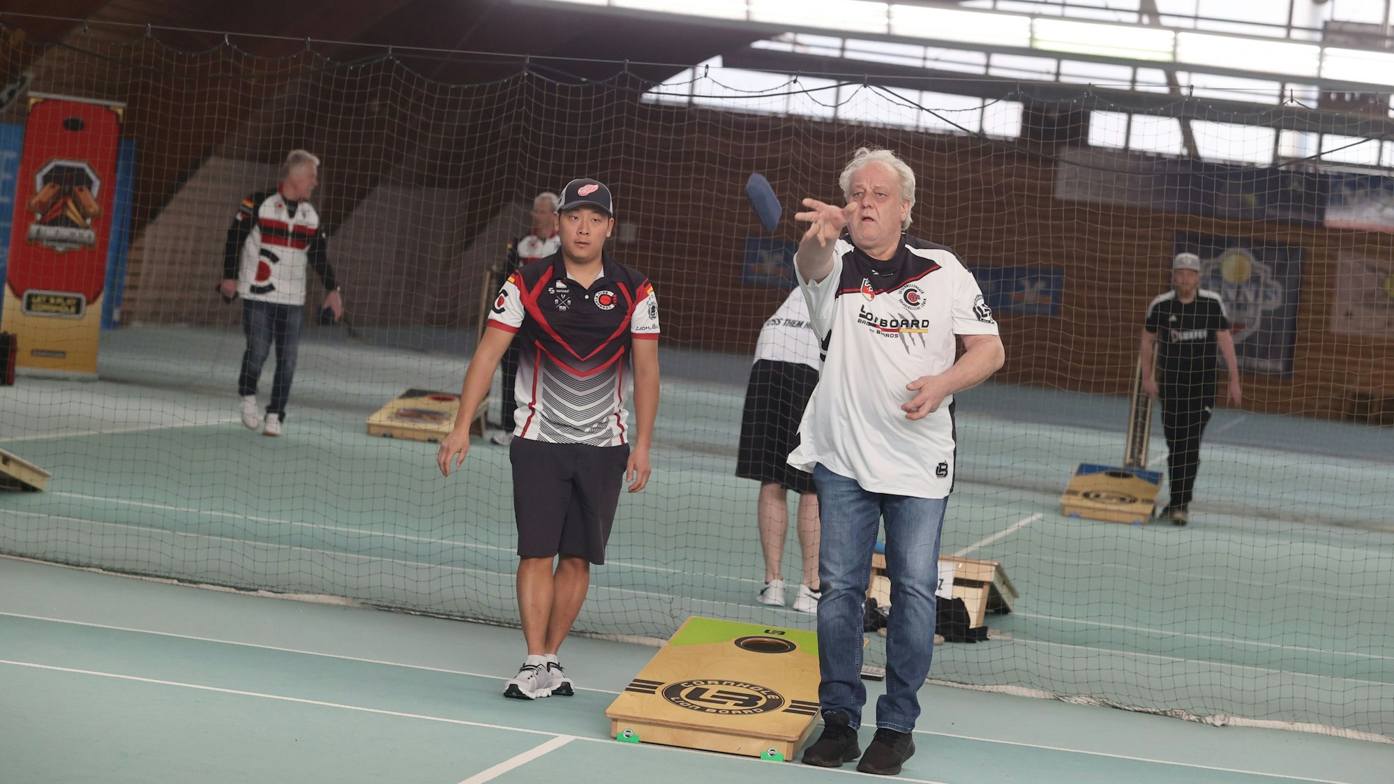 Spielszene aus dem Trendsport Cornhole, ein Mann wirft ein mit Granulat gefülltes Säckchen