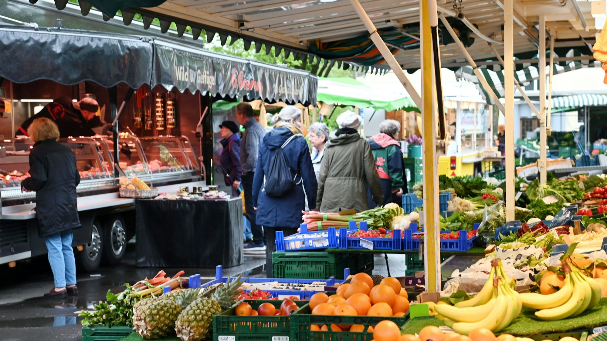 Menschen gehen an den Ständen des Wochenmarkts am Auerbachplatz in Köln-Sülz vorbei. Foto von Alexander Schwaiger
