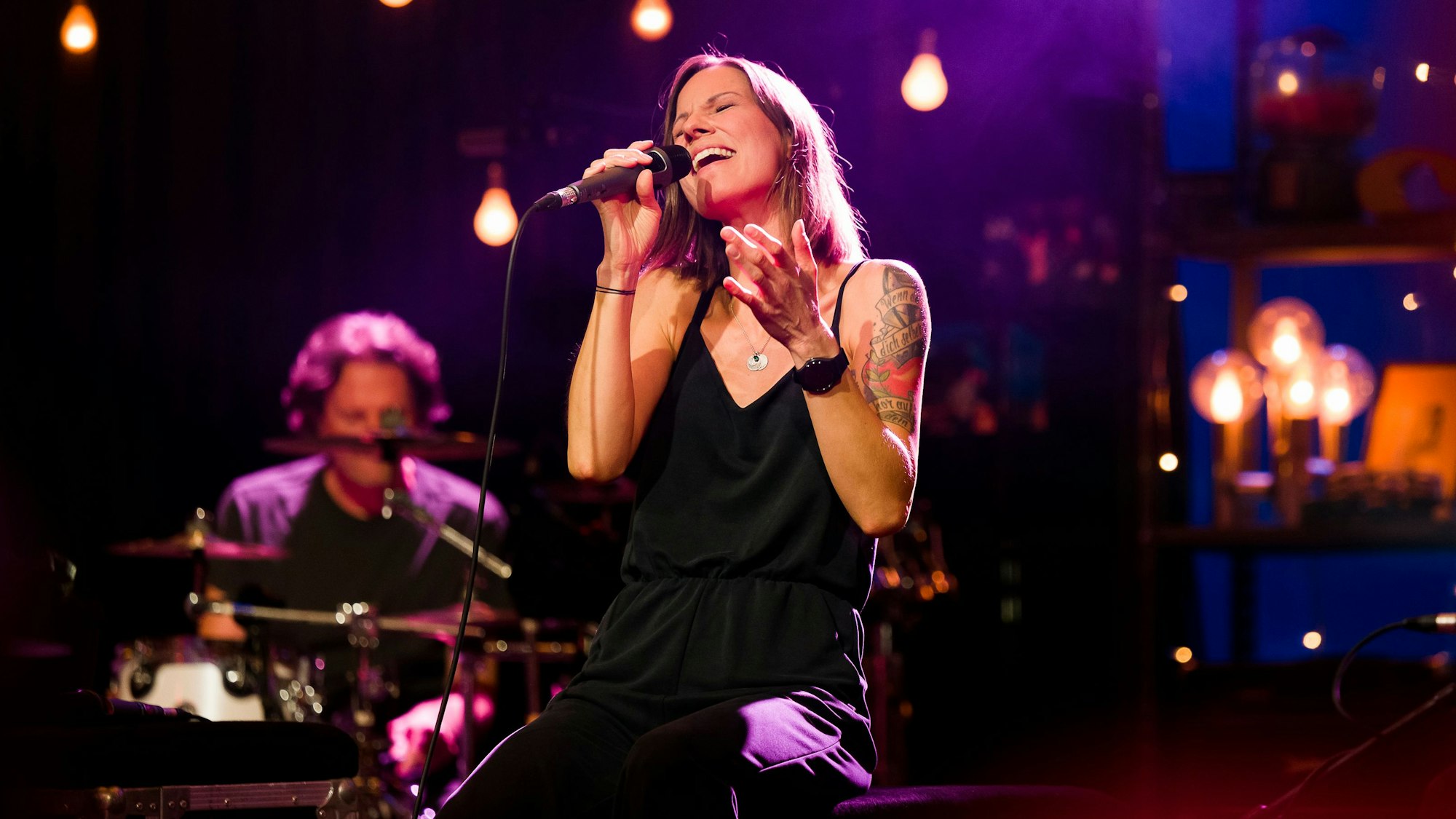 Christina Stürmer sitzt auf einem Stuhl und singt.