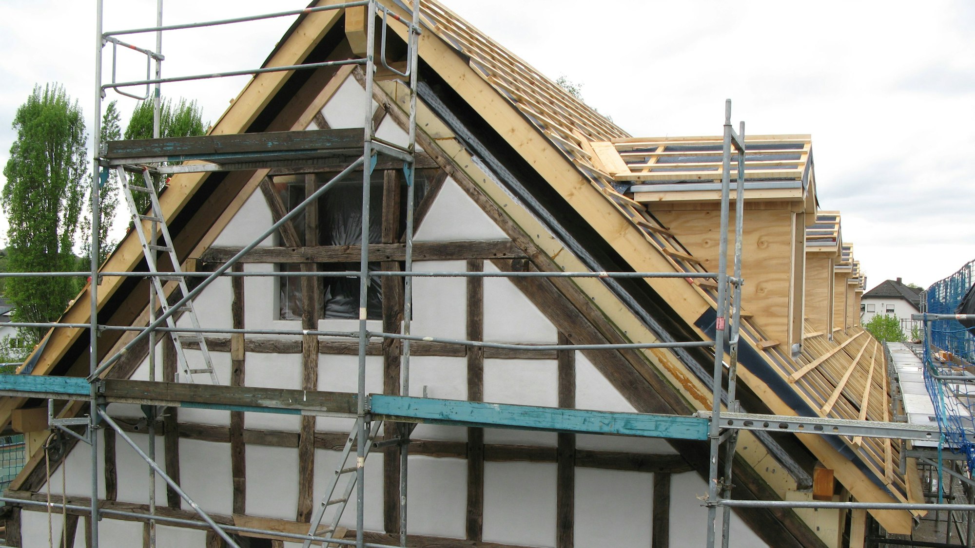 Das Bild zeigt den Giebel und eine Dachseite eines eingerüsteten Fachwerkbaus.