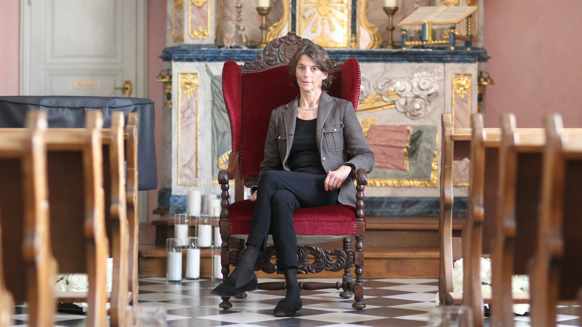 Eine Frau sitzt auf einem Stuhl in einem Kirchenraum