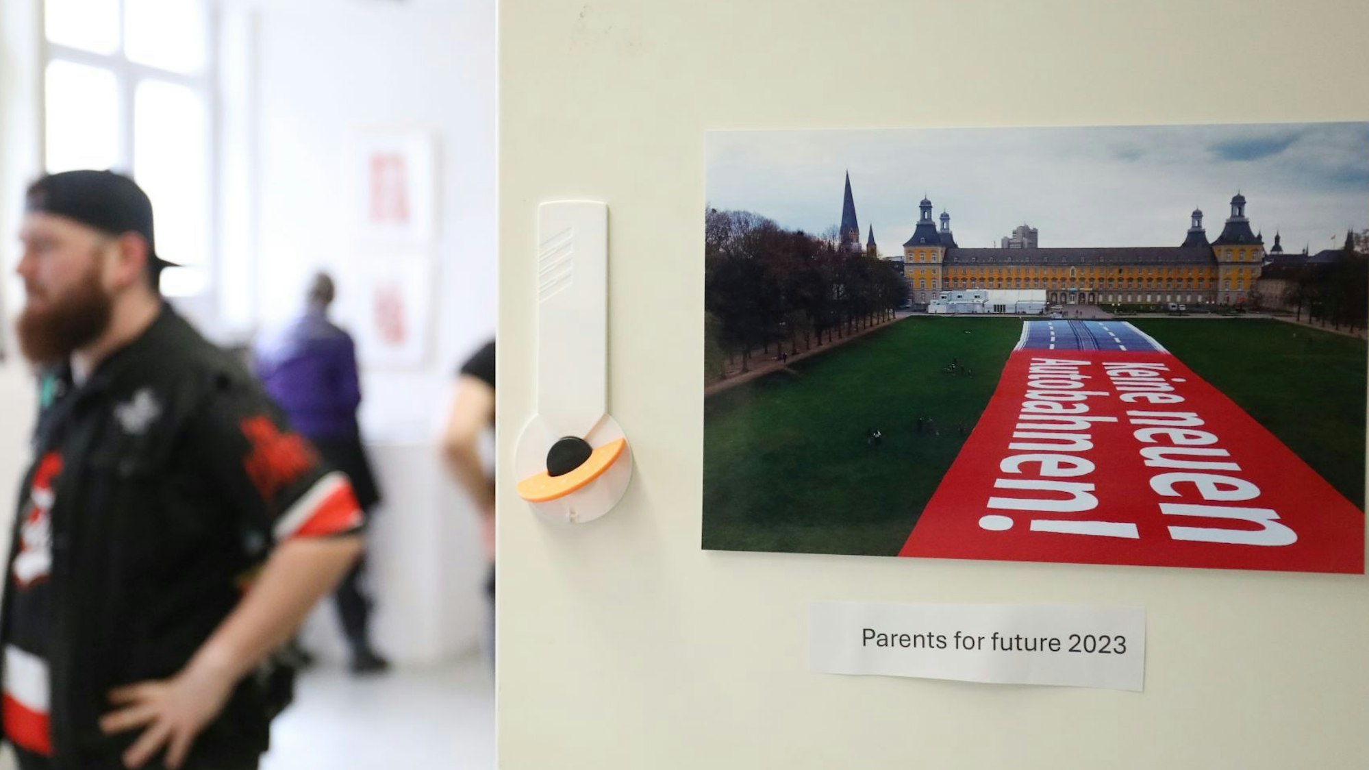 Ein Besucher in der Ausstellung neben einem Foto, das den Bonner Hofgarten und die Universität zeigt.