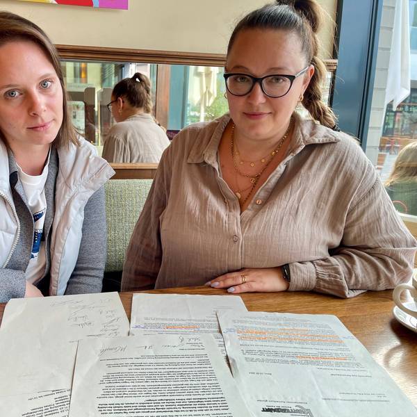 Zwei junge Frauen sitzen an einem Tisch mit Schriftstücken.