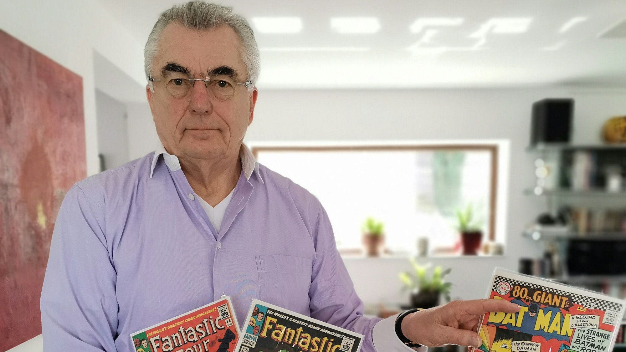 Zu sehen ist Werner Steinheimer, der Comics in der Hand hält.