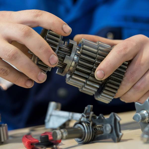 Die Hände eines jungen Mannes halten Metallteile.