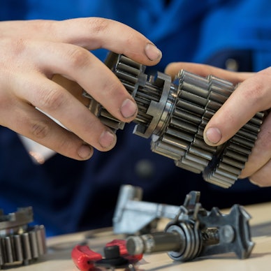 Die Hände eines jungen Mannes halten Metallteile.