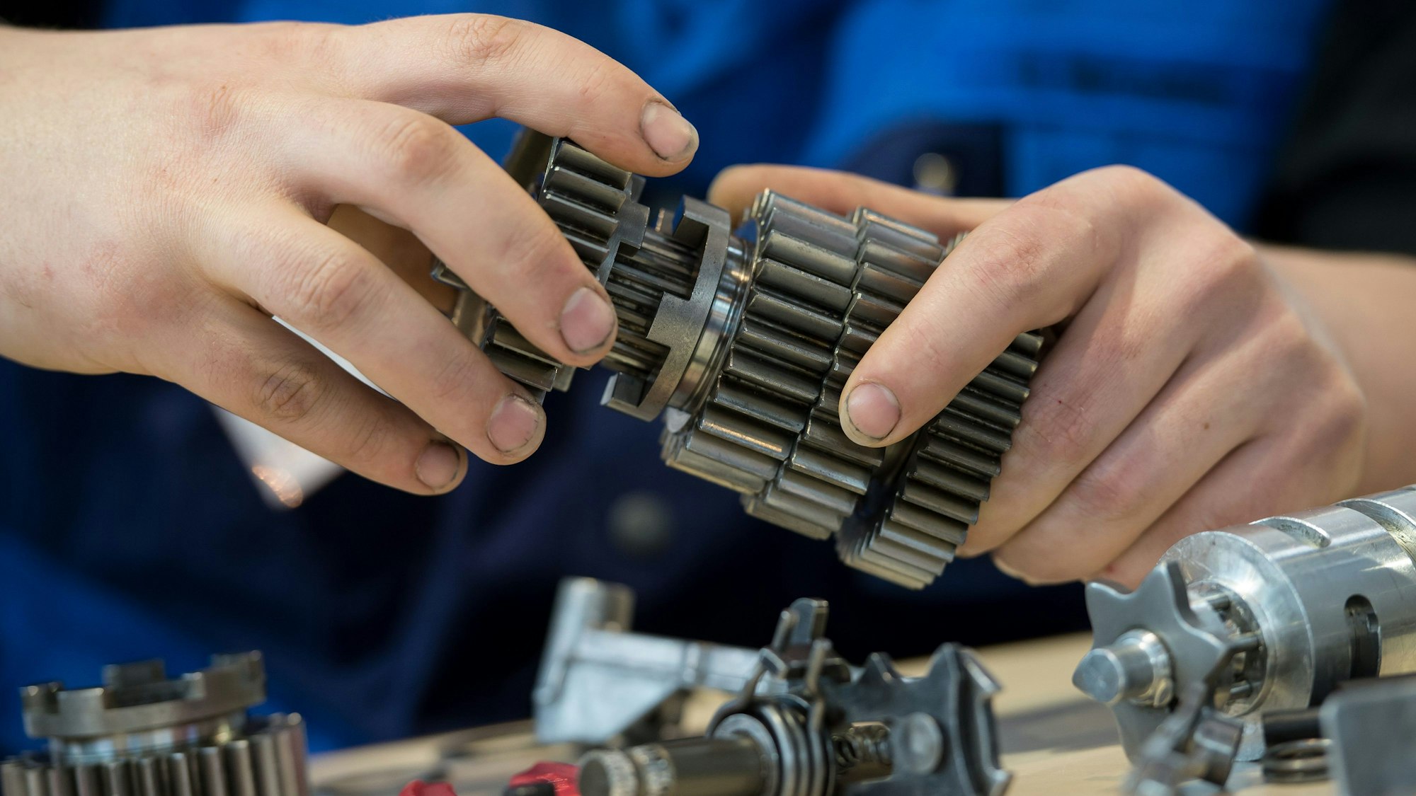 Die Hände eines jungen Mannes halten Metallteile.