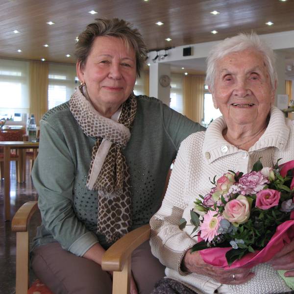 Die 102 Jahre alte Charlotte Seeger sitzt mit einem Blumenstrauß in den Händen neben ihrer 74-jährigen Tochter.