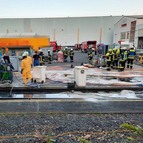 Viele Feuerwehrleute stehen auf einem Firmengelände.