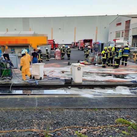 Viele Feuerwehrleute stehen auf einem Firmengelände.