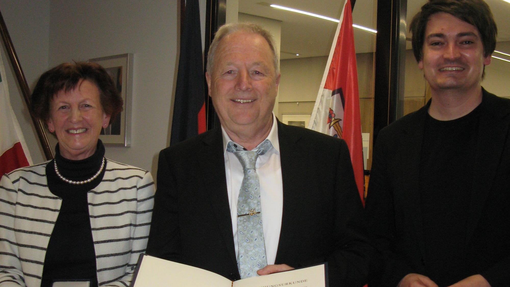 Der mit der Bundesverdienstmedaille ausgezeichnete Hennefer Heiner Krautscheid (71) steht zwischen Vizelandrätin Notburga Kunert und Bürgermeister Mario Dahm.