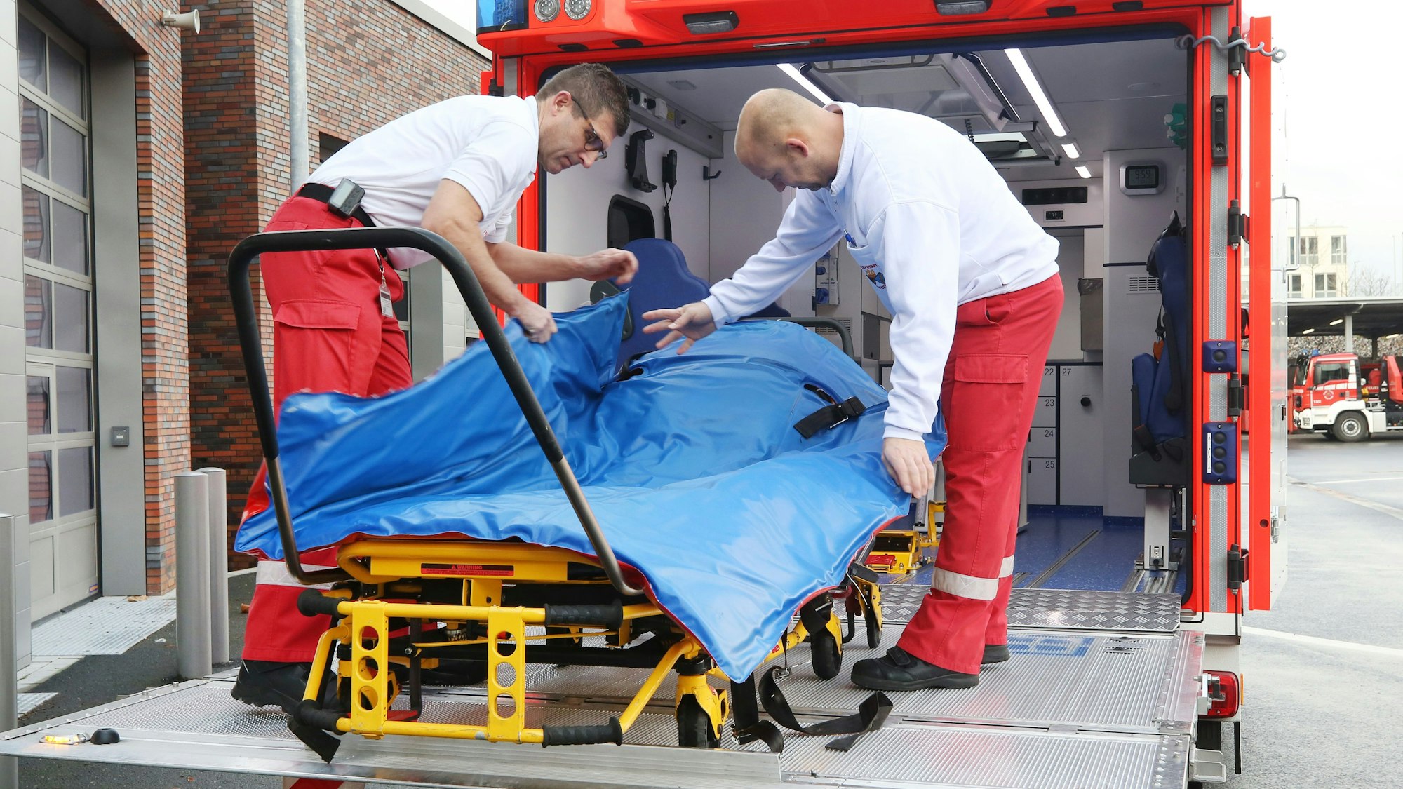 Mit einer Schwerlasttrage hantieren die Feuerwehrleute Oliver Schwarz (l) und Marc Elmhorst auf der Hebebühne des Schwerlastrettungswagens.