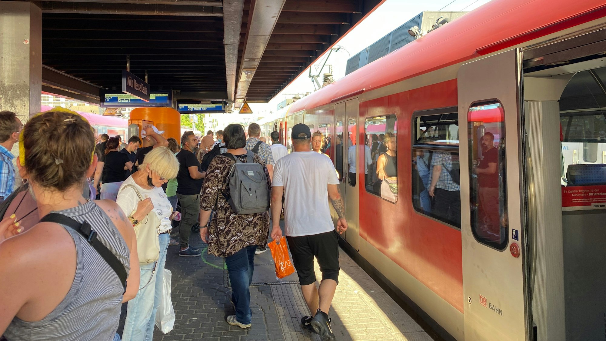 Ein Zug der S-Bahnlinie 11 hält im Sommer an einem vollen Bahnsteig in Köln.