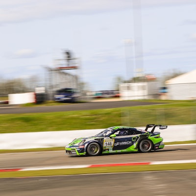 Der Porsche von Tobias Müller bewegt sich schnell auf dem Nürburgring. Der Hintergrund verschwimmt.