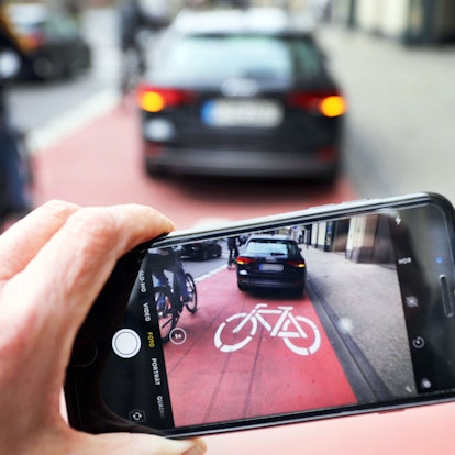 Symbolbild: Ein Auto parkt auf einem Fahrradweg, ein anderer macht ein Foto von davon.