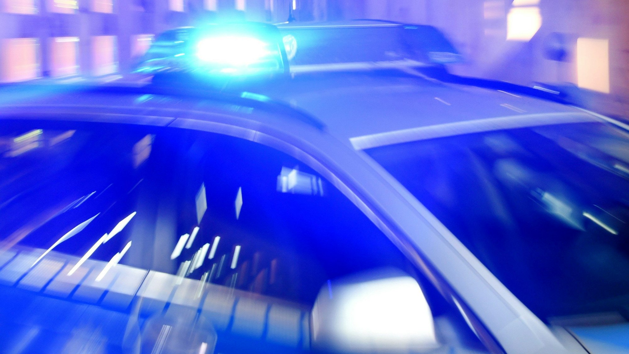 Ein Streifenwagen der Polizei steht mit eingeschaltetem Blaulicht auf der Straße.