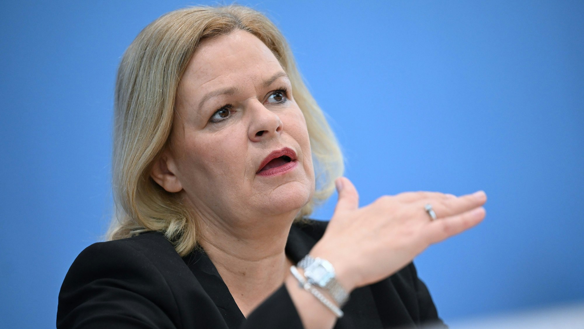 Zu sehen ist Bundesinnenministerin Nancy Faeser vor einem blauen Hintergrund.