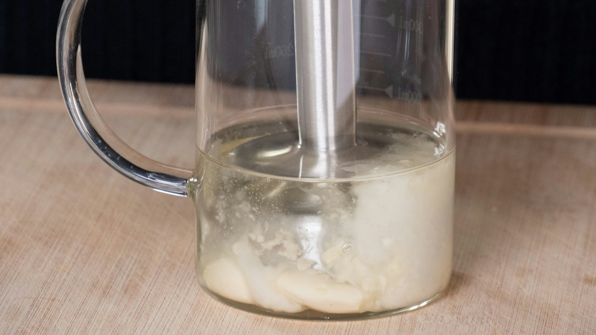 Mit einem Pürierstab werden die Knoblauchzehen und das Öl in einem Gefäß gemixt.