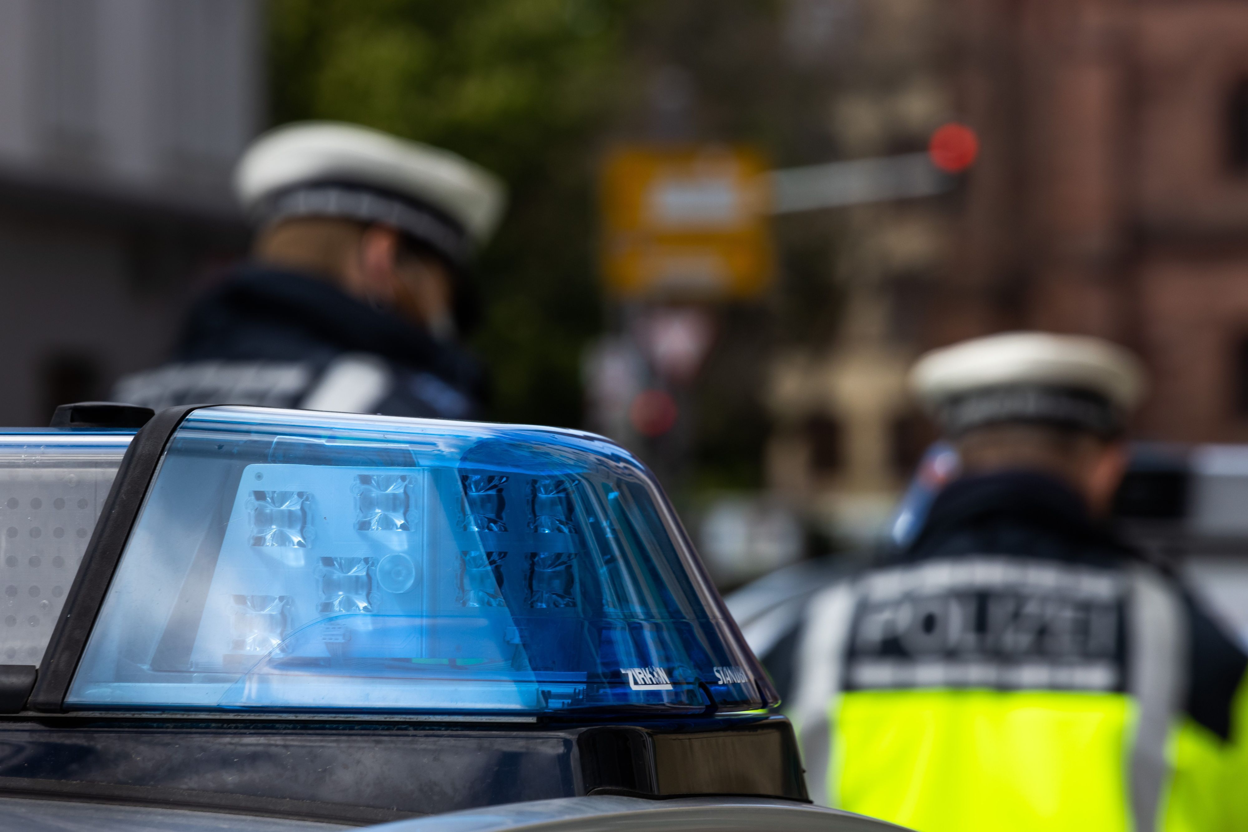 Zwei Polizeibeamte stehen zwischen zwei Einsatzfahrzeugen der Polizei.