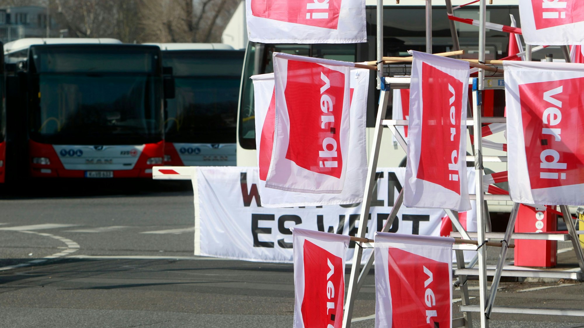 Am Betriebshof der Kölner Verkehrs-Betriebe (KVB) stehen angesichts eines Verdi-Warnstreiks im öffentlichen Nahverkehr mehrere leere Busse, im Vordergrund hängen Verdi-Fahnen.