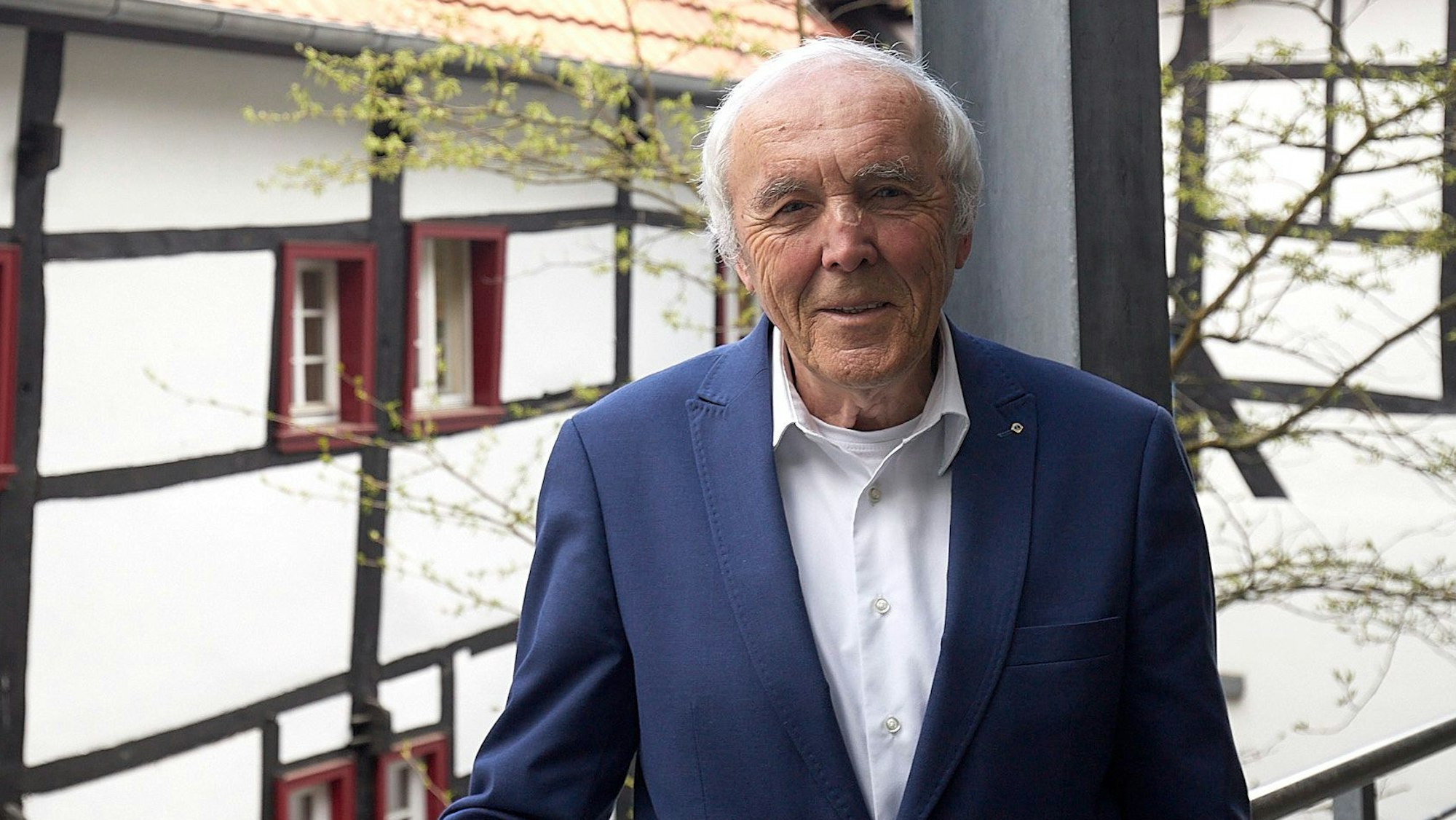 Das Bild zeigt Frank Günter Zehnder. Im Hintergrund sind Fachwerkhäuser zu sehen.