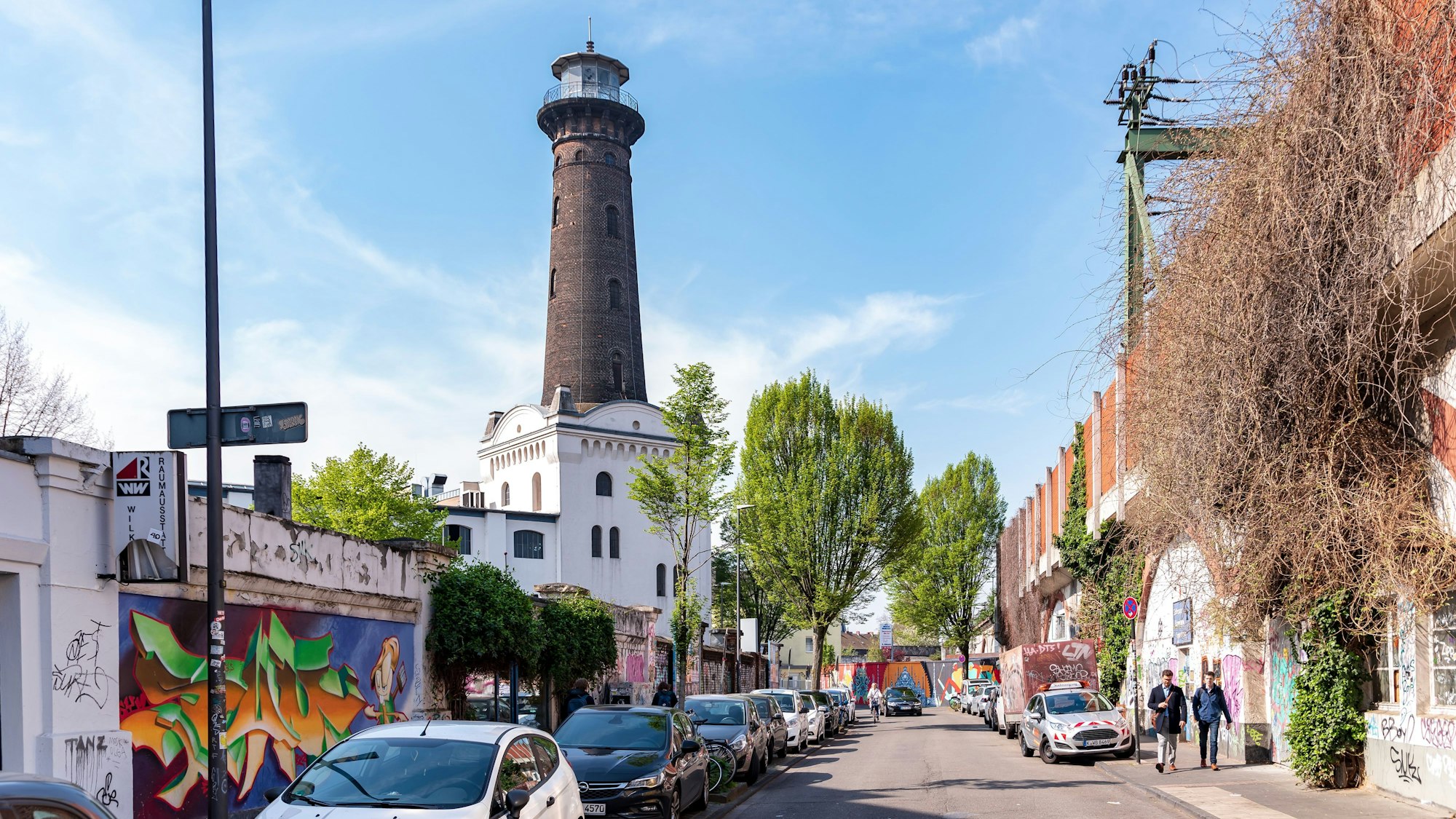 Eine Straße an der viele Autos geparkt sind und im Hintergrund der Heliosturm