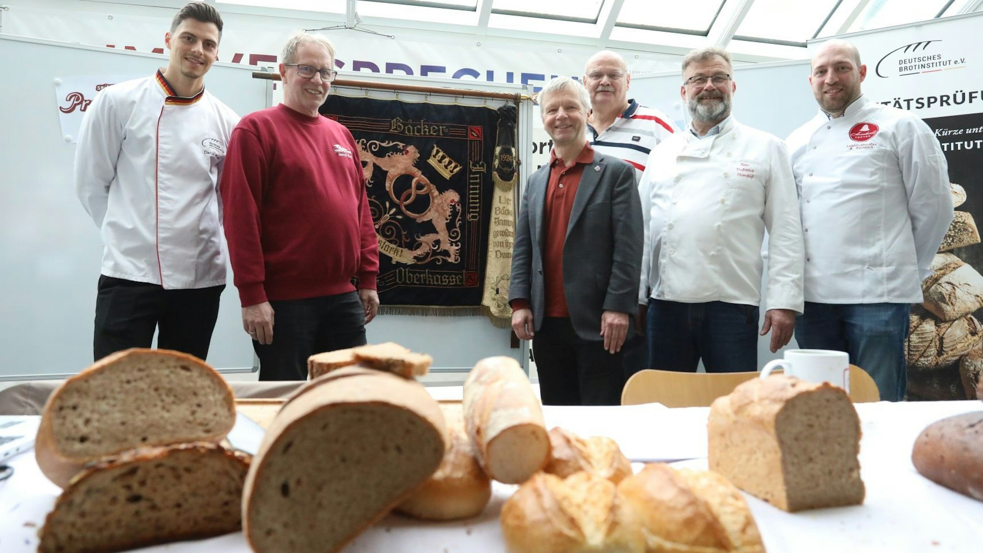 Fünf Männer stehen hinter einem Tisch, auf dem mehrere Brotsorten und Brötchen liegen.