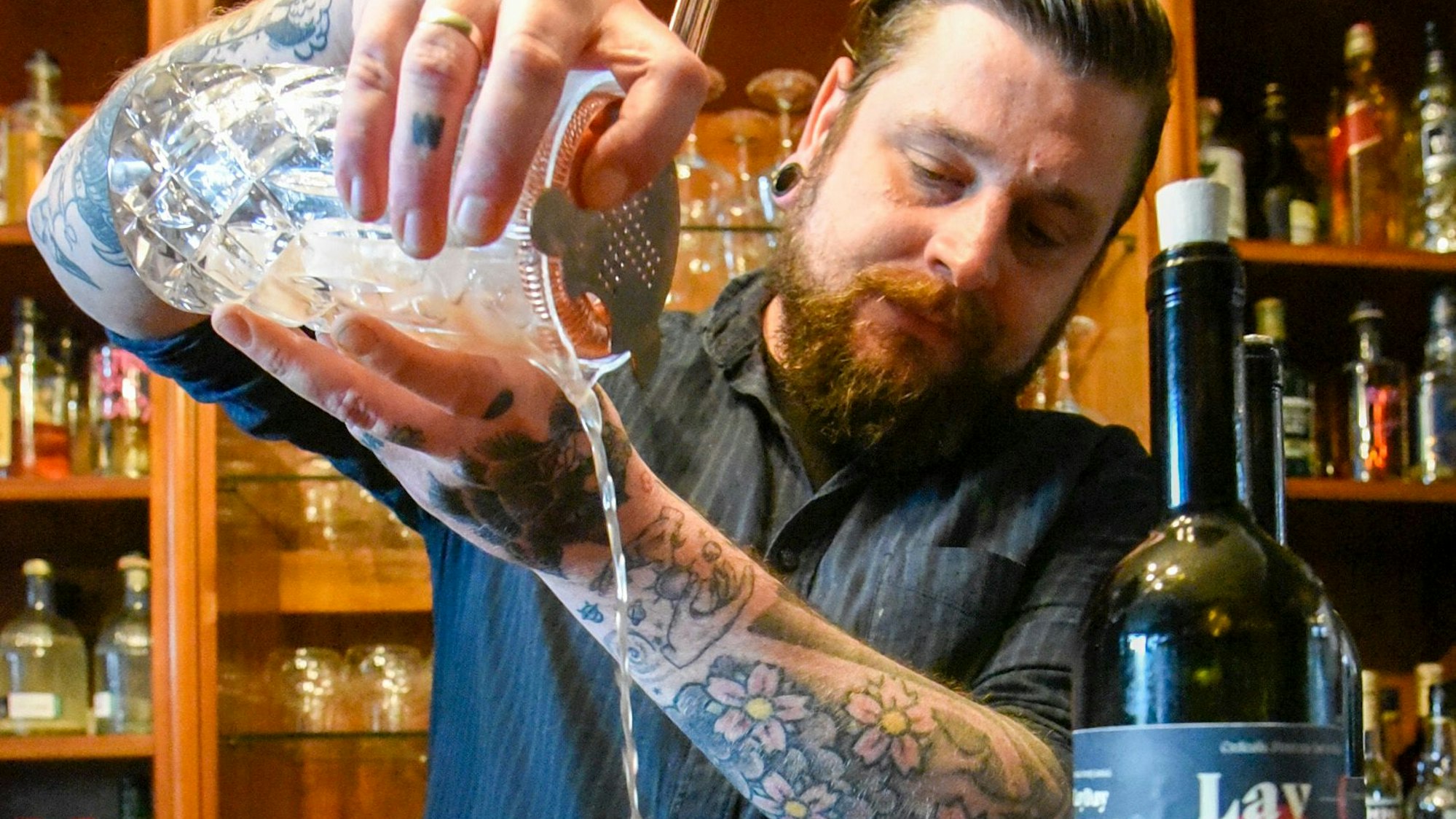 Auf dem Bild ist der Barinhaber beim Mixen eines Drinks zu sehen.