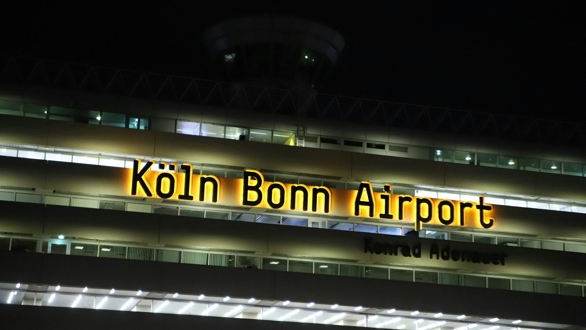 Das Logo Köln Bonn Airport leuchtet am Terminalgebäude des Flughafens.