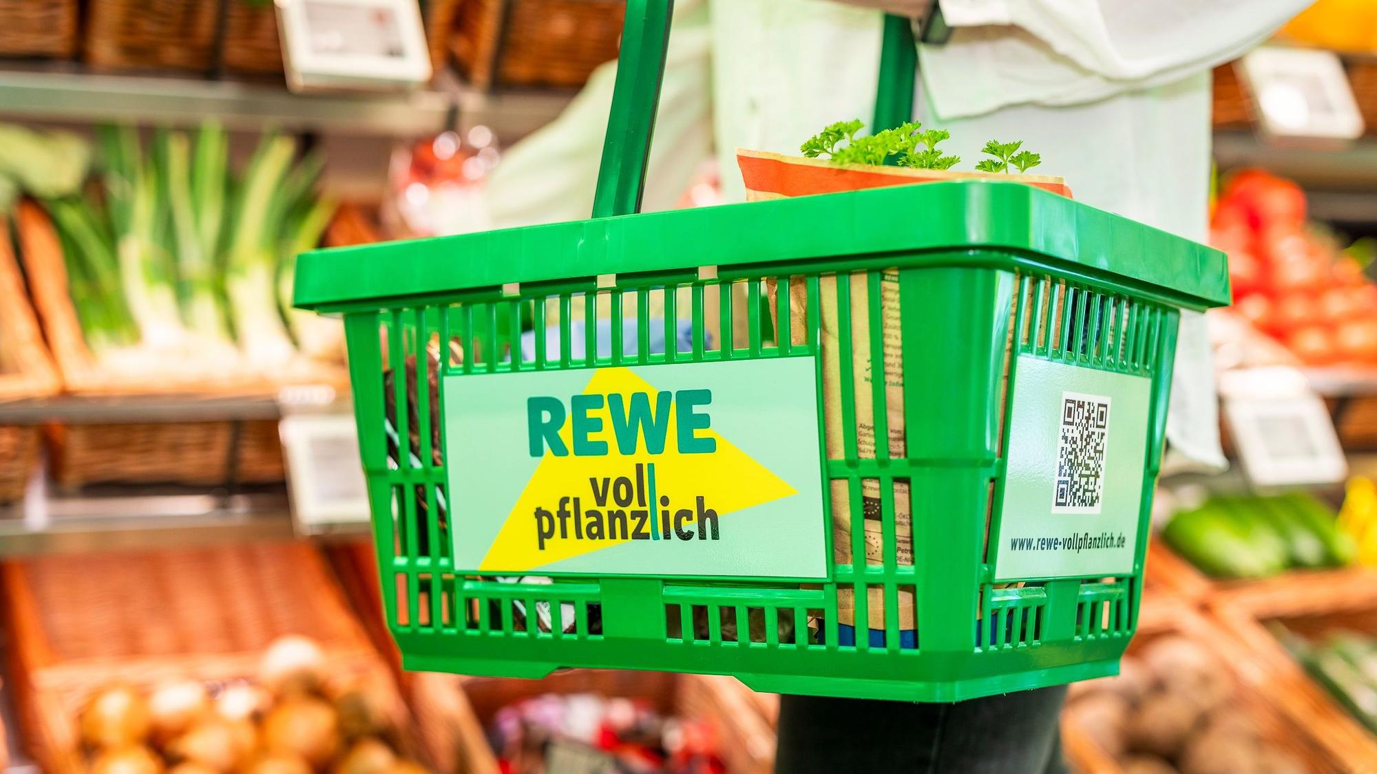 Zu sehen ist ein grüner Einkaufskorb in einem Supermarkt.