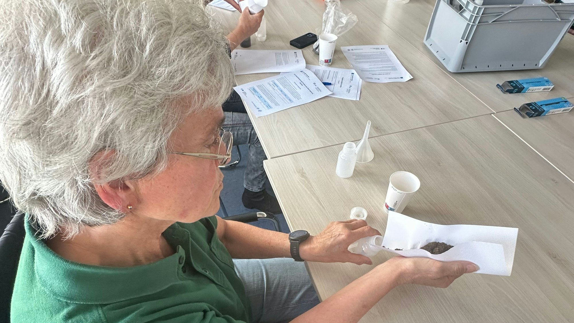 Brigitte Klöckner aus Hangelar füllt ihre mitgebrachte Erde in eine Analyseflasche.
