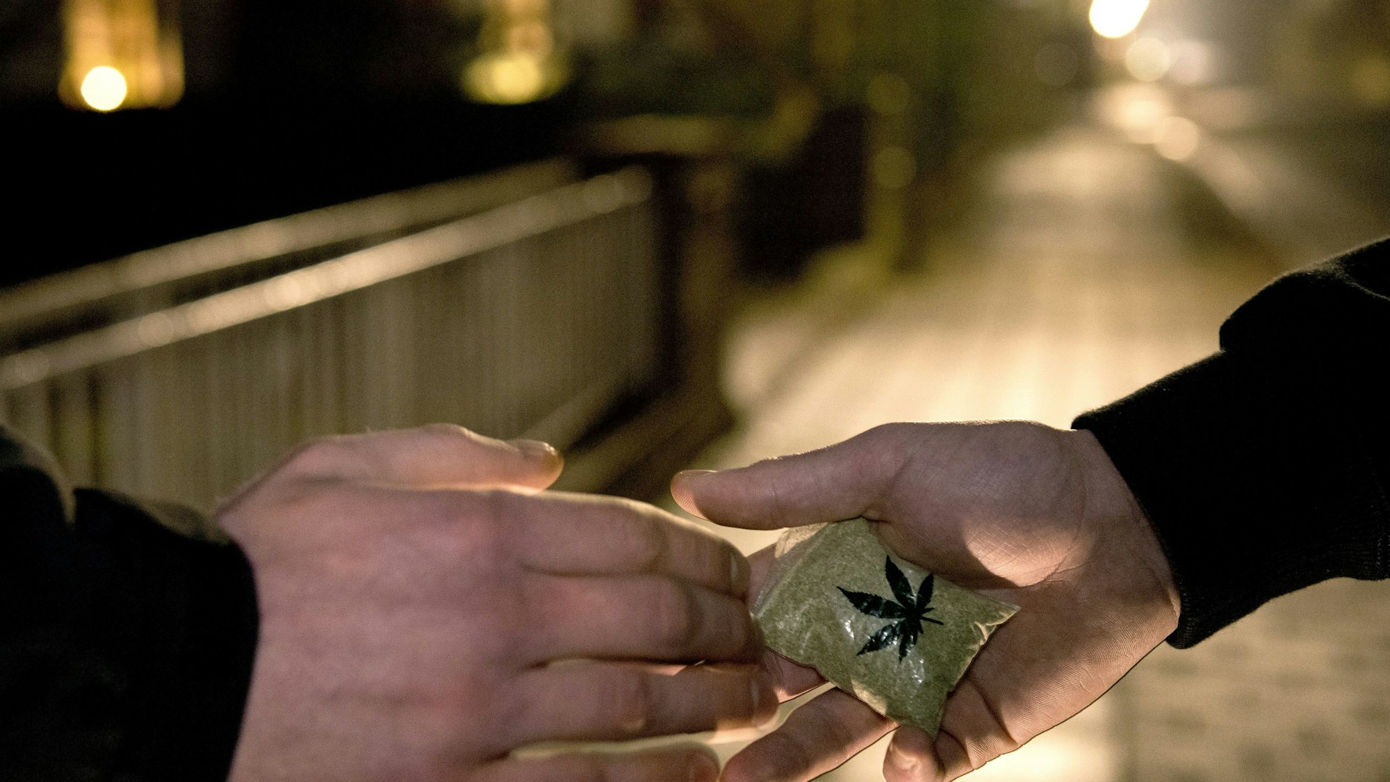 Das Bild zeigt die Übergabe von Drogen in der Dunkelheit.