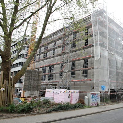 Die Baustelle für ein großes, eingerüstetes Haus mit verhängter Fassade