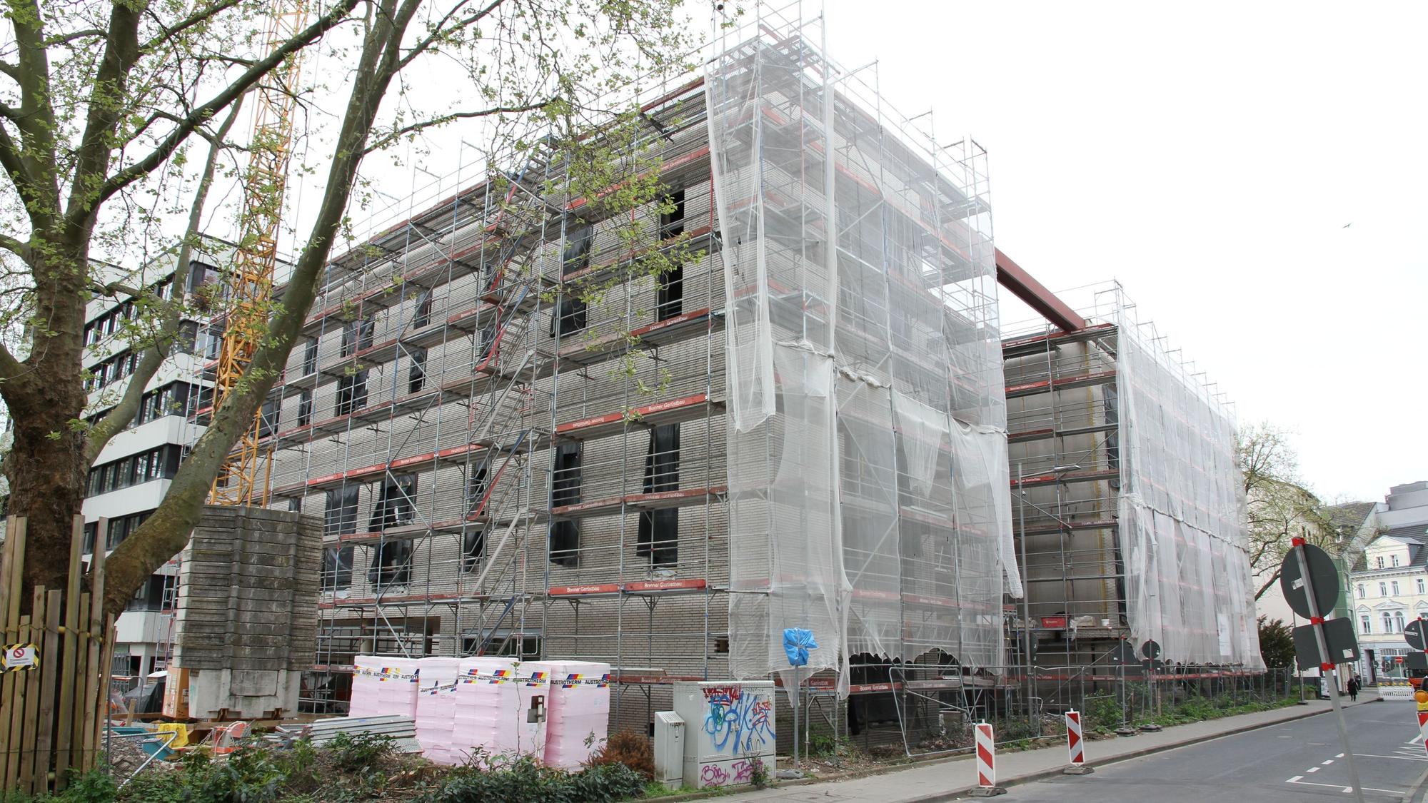 Die Baustelle für ein großes, eingerüstetes Haus mit verhängter Fassade