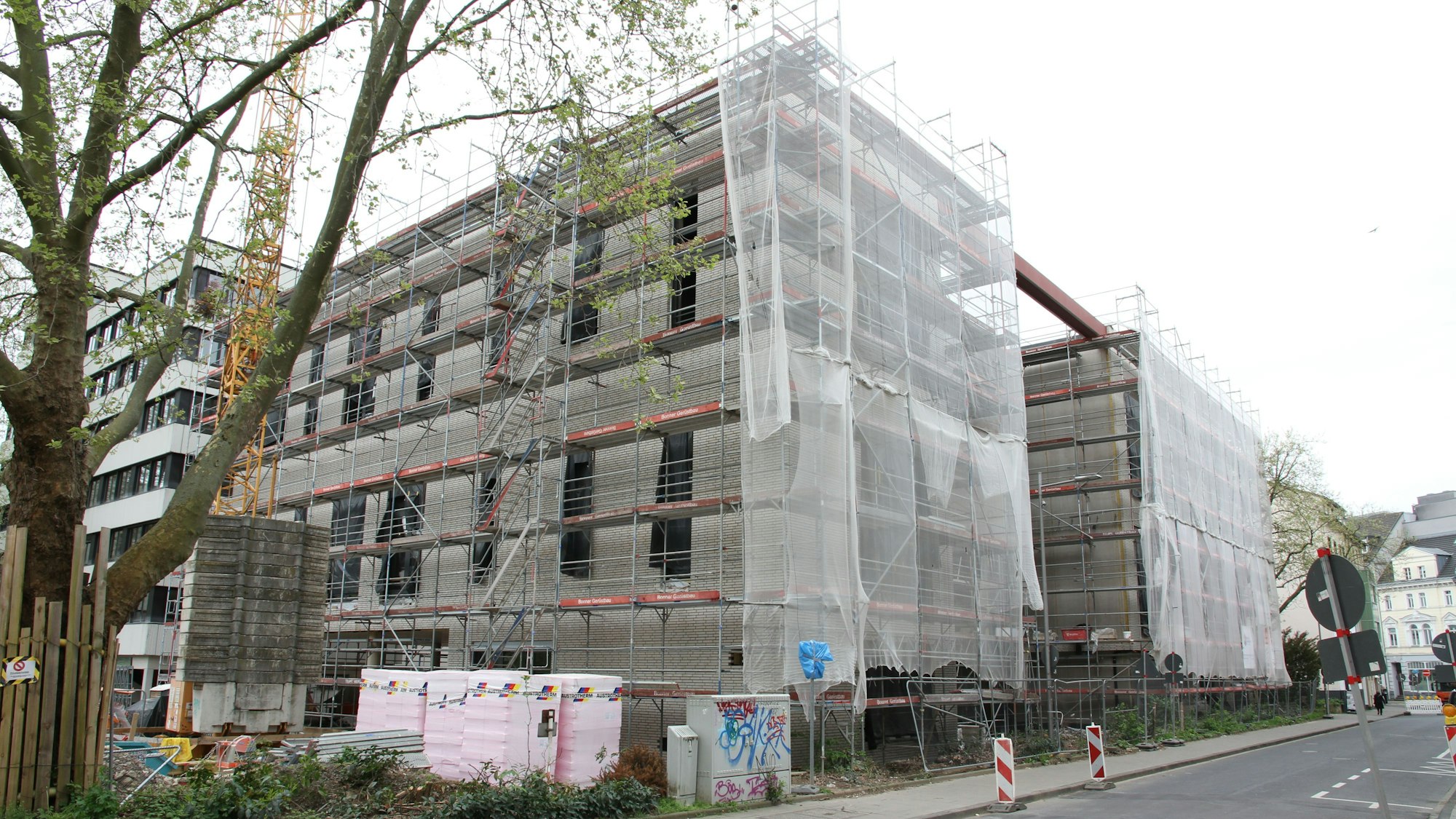 Die Baustelle für ein großes, eingerüstetes Haus mit verhängter Fassade