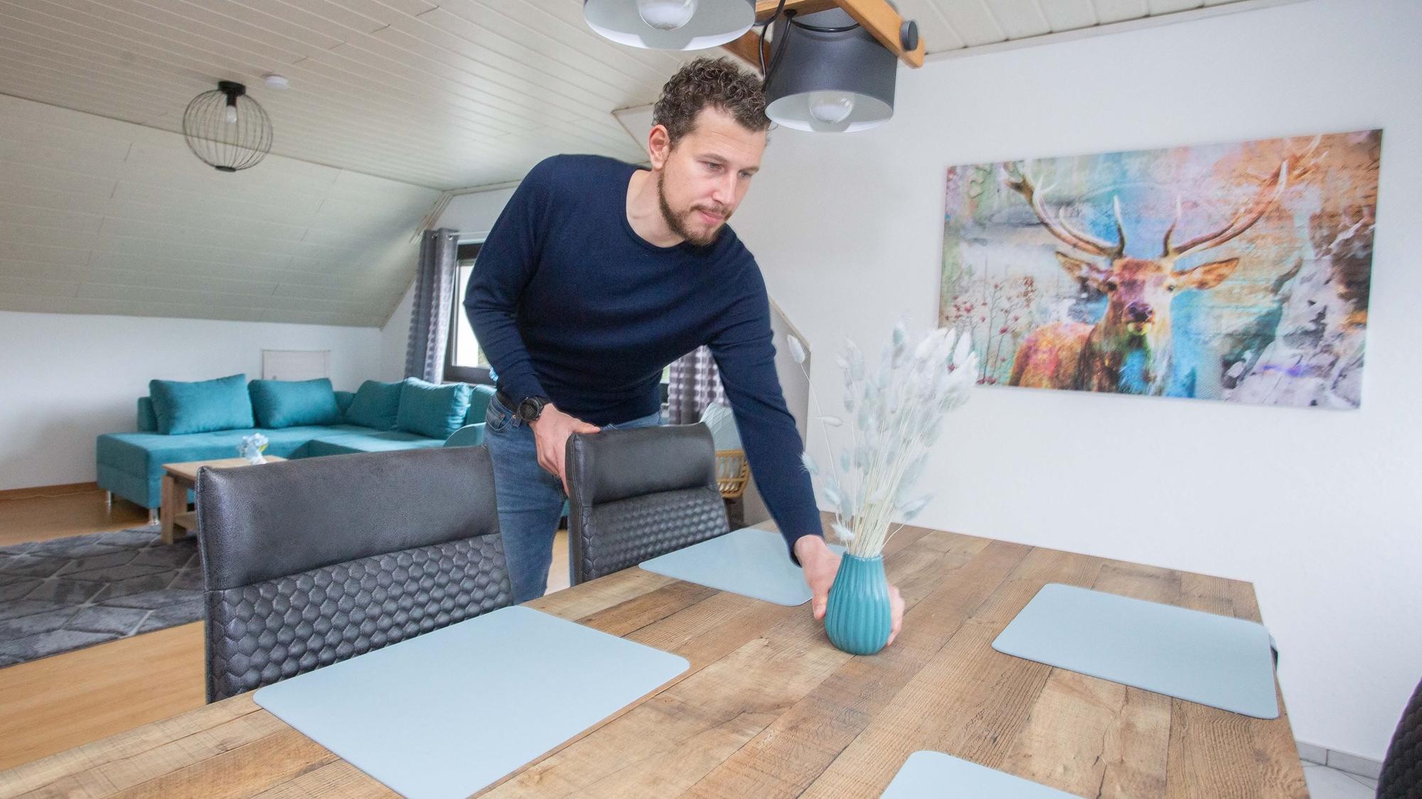 Ferienwohnung im Hotel Engelskirchen in Bicken, Chef Peter Breidenbach richtet einen Tisch, er hält eine Vase in der Hand.