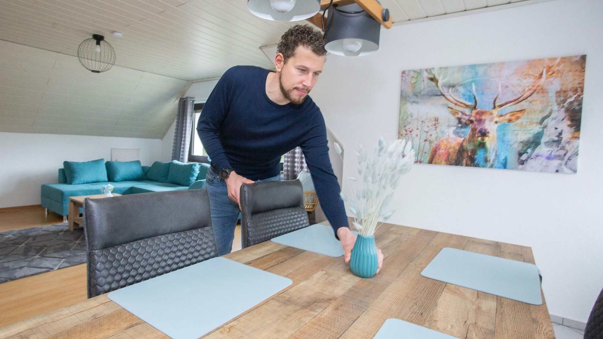Ferienwohnung im Hotel Engelskirchen in Bicken, Chef Peter Breidenbach richtet einen Tisch, er hält eine Vase in der Hand.