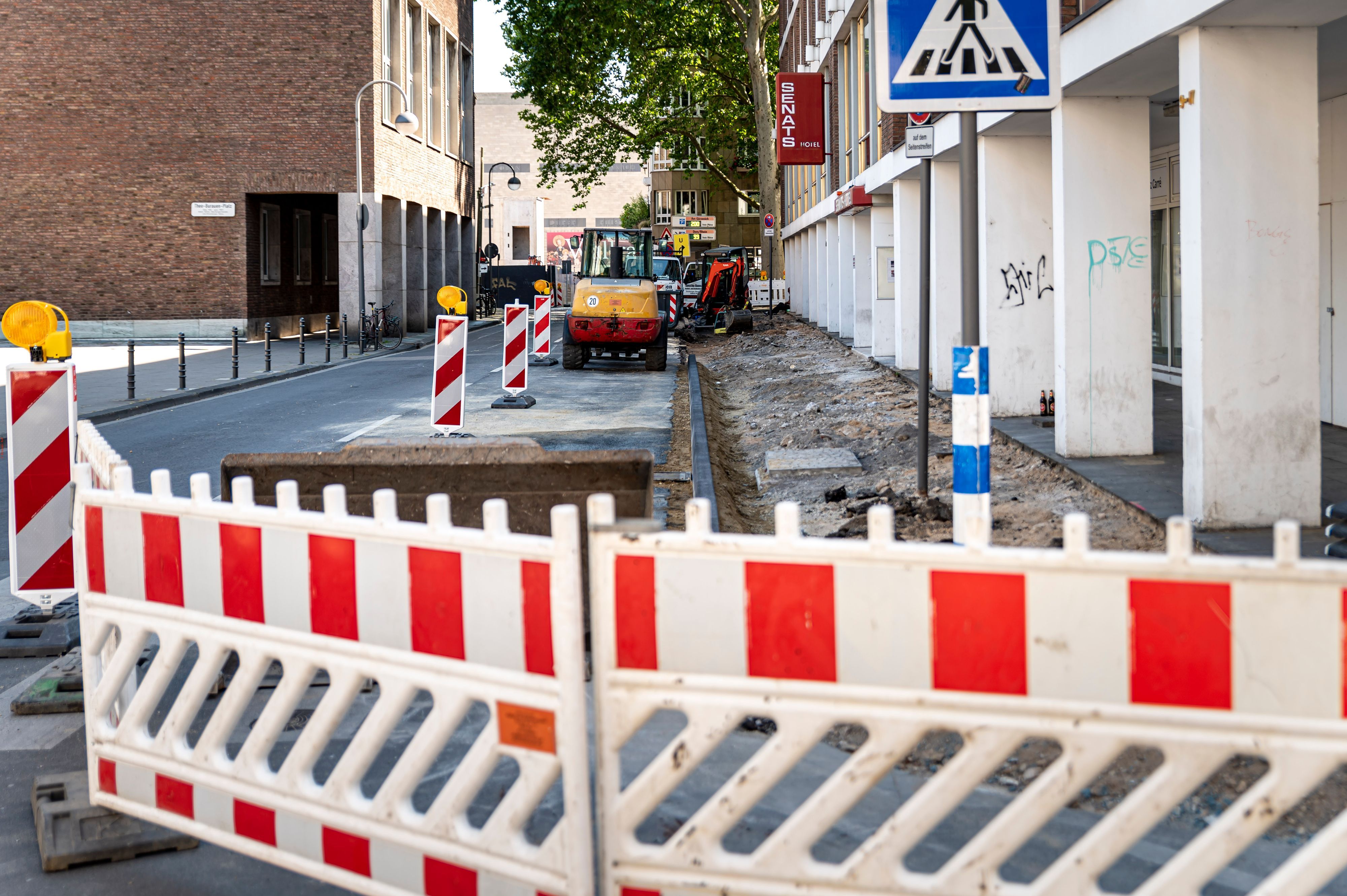 Auf dem Foto sind ein aufgerissener Bürgersteig und rot-weiße Absperrschilder zu sehen.