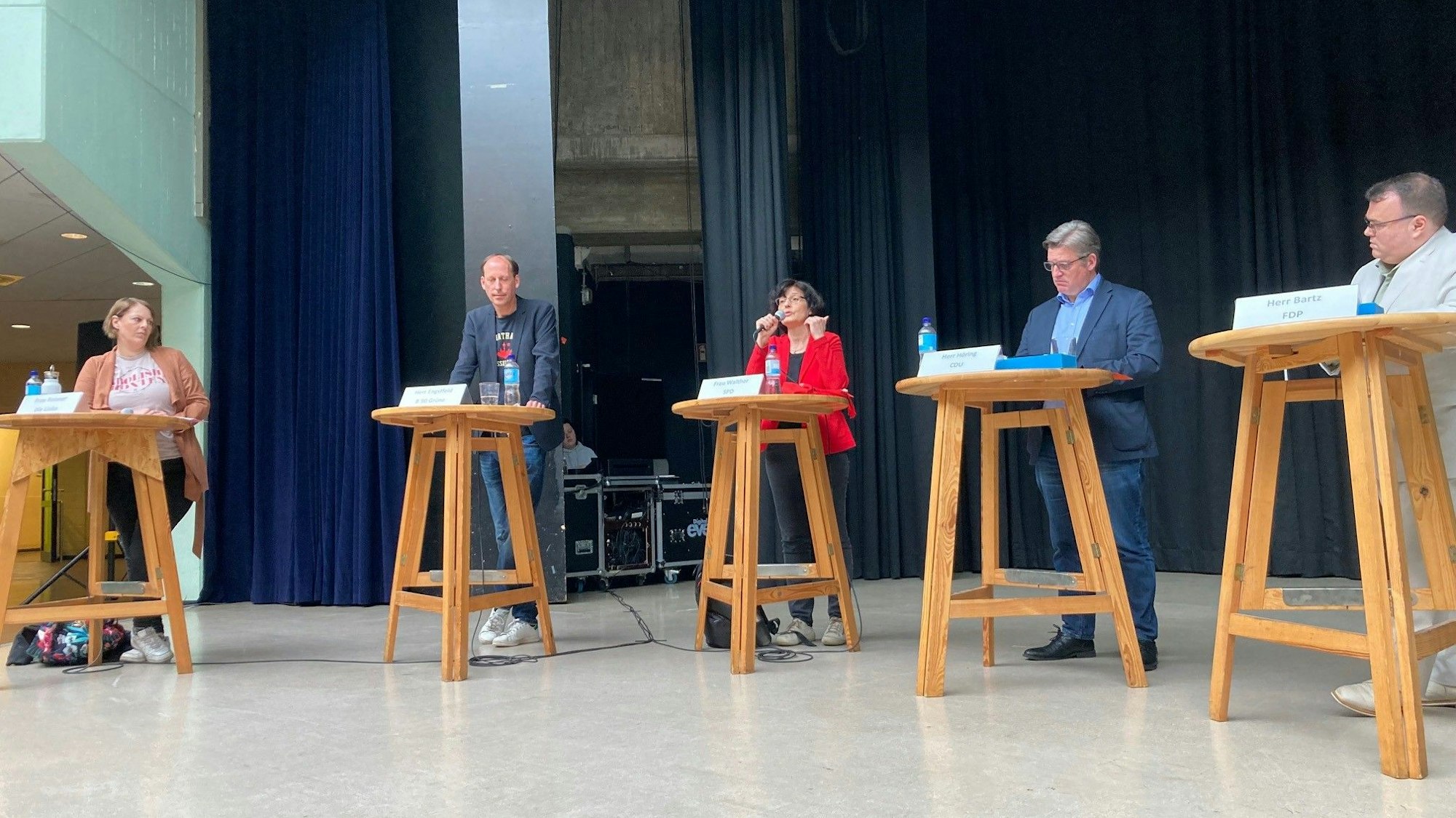 Die fünf Kandidaten stehen an einzelnen Stehtischen.