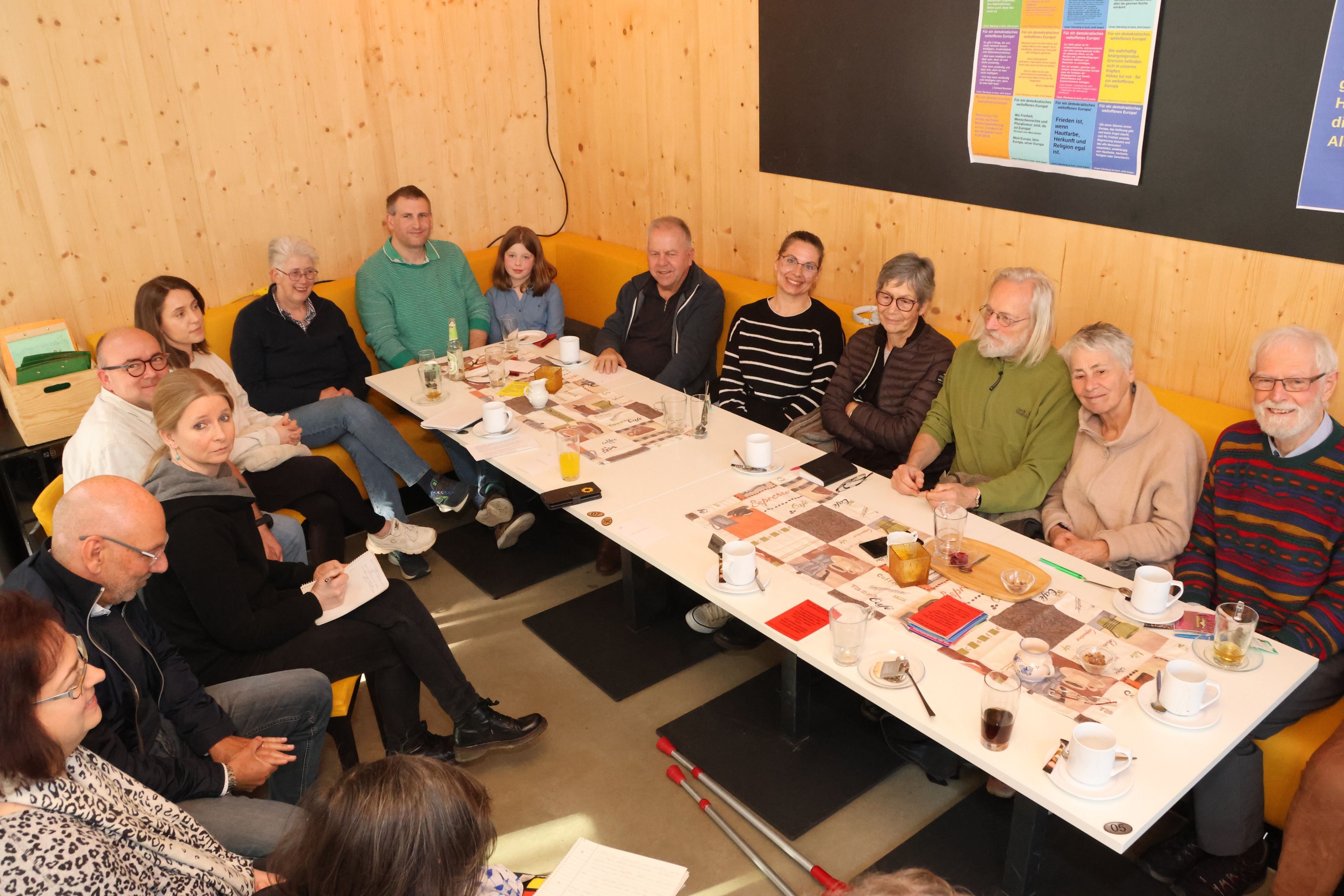 Mehrere Menschen sitzen gemeinsam um einen langen Tisch herum.