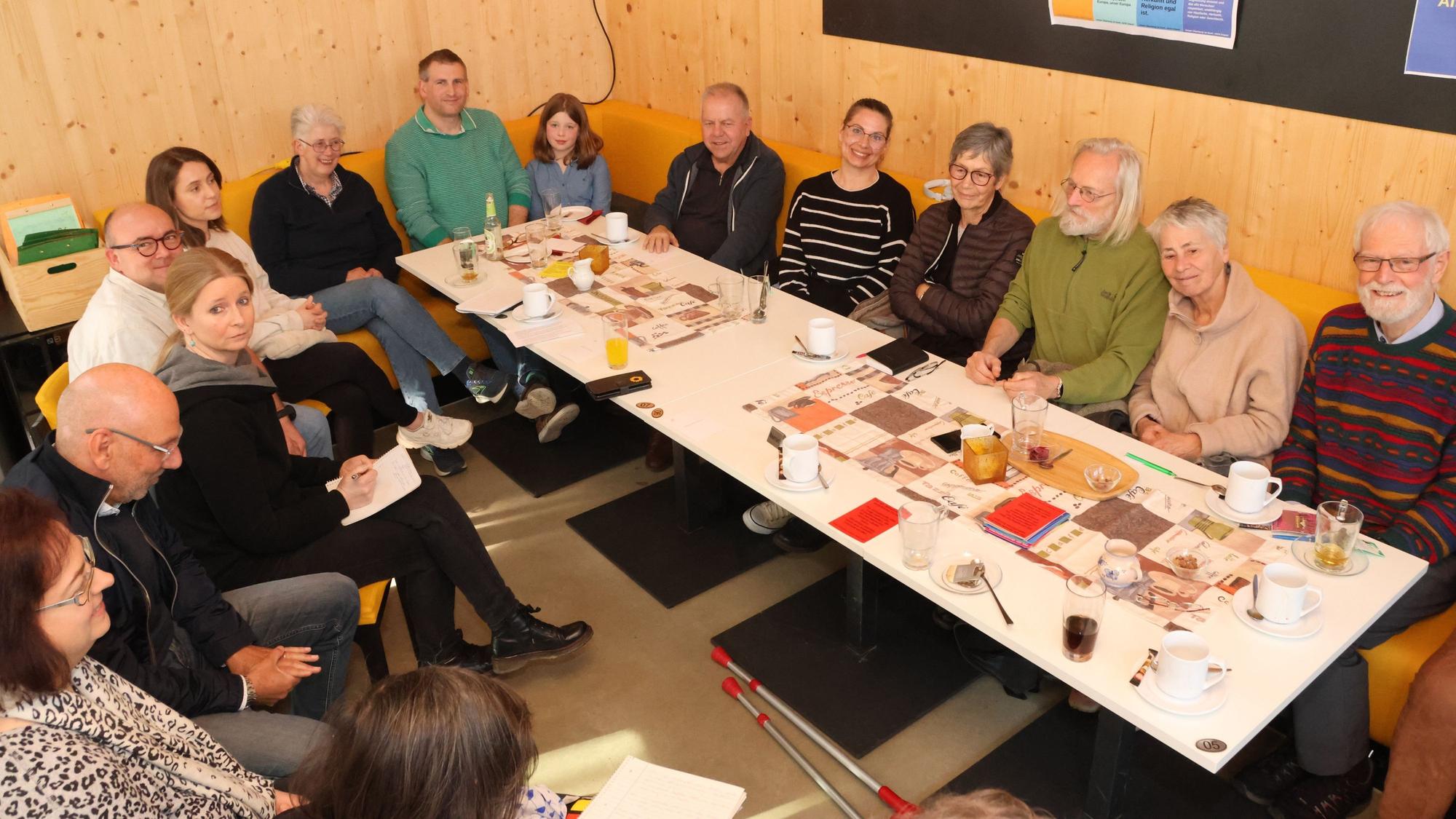 Mehrere Menschen sitzen gemeinsam um einen langen Tisch herum.