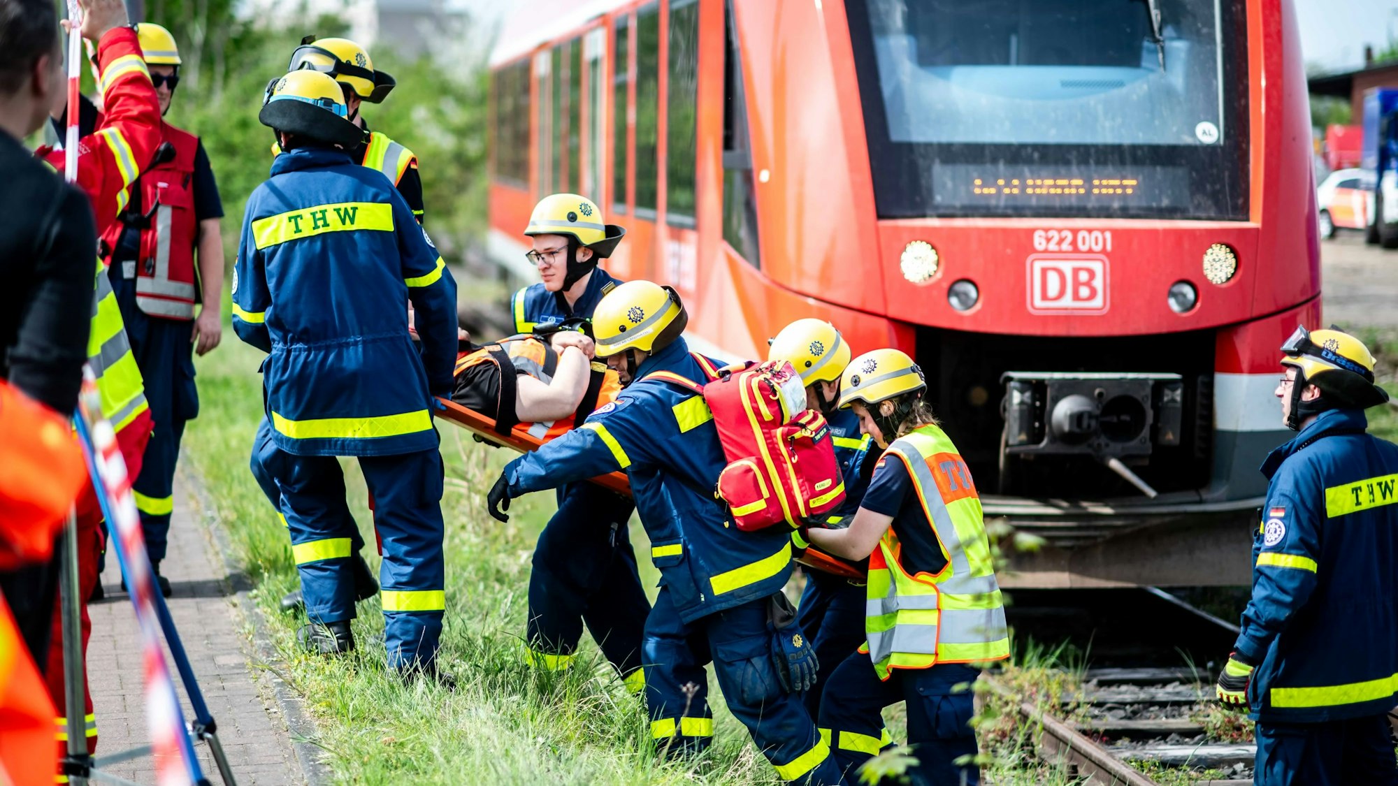 Das Bild zeigt einige Mitarbeiter des THW, die eine verletzte Person eine Böschung hinauf tragen.